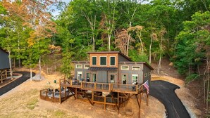 A two-story house with a deck, surrounded by trees and a winding driveway. - Sunsets on Garren Cove (Morganton)