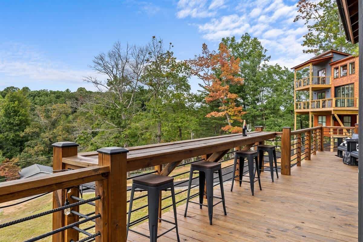 Una terraza de madera con taburetes, barandilla y un edificio de varios niveles.