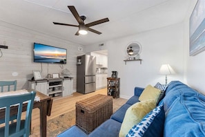 Un espacio habitable compacto con kitchenette, comedor, sofá y ventilador de techo.