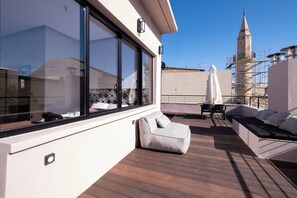 A rooftop terrace with a sofa, a table, and a view of a tower. - Citrus Daliani Rooms (Chania)