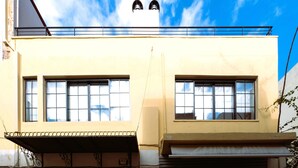 En bygning med to store vinduer, en balkon og en hvid facade.