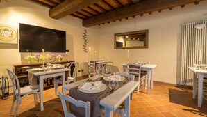 A dining area with a rustic wooden ceiling, a flat-screen TV, and a dining table set for four. - Relais La Costa by Interhome (Monteriggioni)