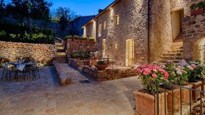 A stone building with a courtyard, outdoor seating, and potted plants. - Relais La Costa by Interhome (Monteriggioni)