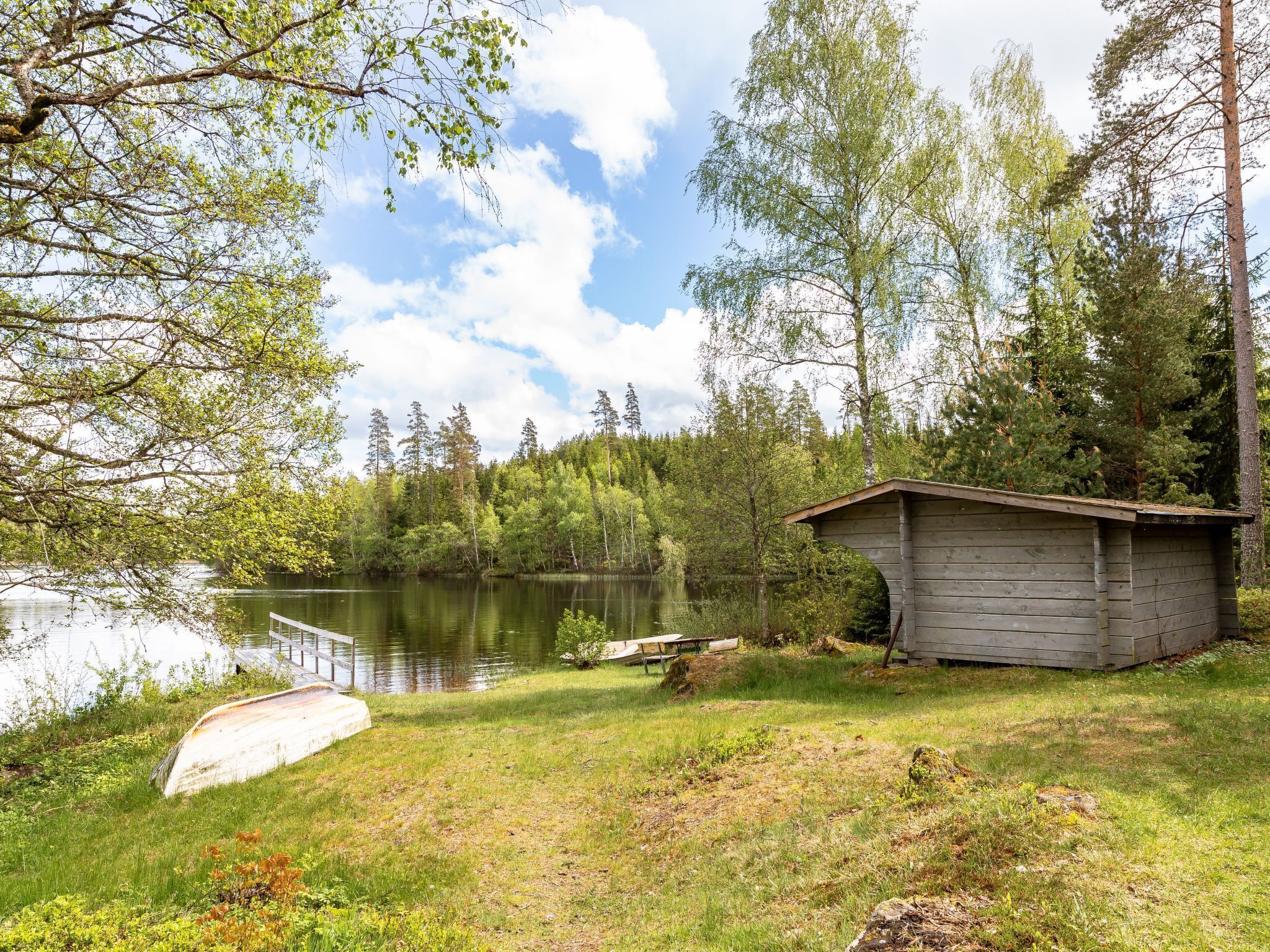 A lakeside cabin with a dock extending into the water, surrounded by dense forest.