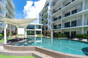 Un hôtel moderne doté d’une piscine centrale, de nombreux balcons et d’un jardin bien entretenu.