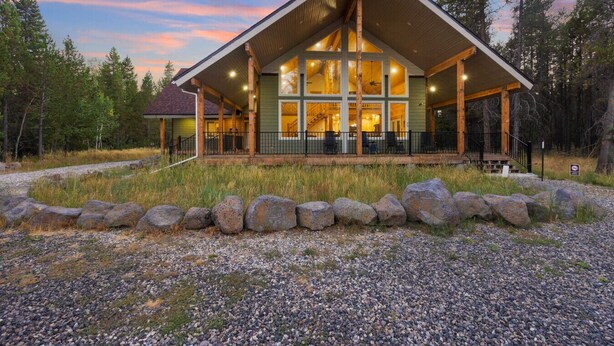 A lodge with a large porch, multiple windows, and a stone pathway leading to the entrance. - Grandpa`s Cabin | Sleeps 22, Near Yellowstone, Hot Tub, Family Friendly! (Island Park)