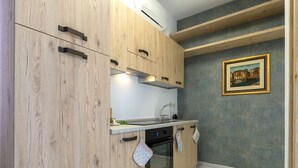 A compact kitchen with wooden cabinets, a built-in oven, and a sink. - Domus Flavia by Interhome (Olbia)