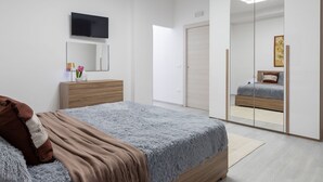 A modern bedroom with a bed, a dresser, a TV, and a large mirror. - Domus Flavia by Interhome (Olbia)