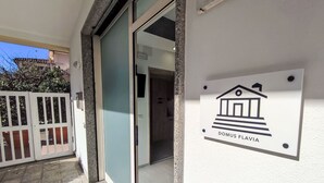 A building entrance with a sign reading "DOMUS FLAVIA" and a gated area with a view of the street. - Domus Flavia by Interhome (Olbia)