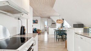 Een moderne keuken met een inbouwfornuis, een eethoek met tafel en stoelen, en een compact keukenblok.