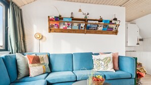 Een moderne woonkamer met een blauwe modulaire bank, een houten boekenkast en een decoratieve schaal op een tafel.