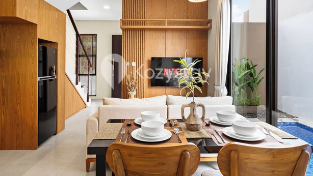 Una sala de estar moderna con comedor, paneles de madera, un televisor de pantalla plana y vista a una piscina.