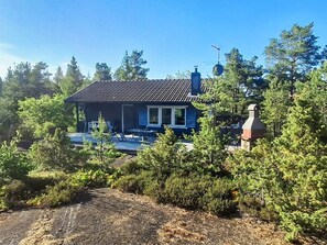 A house with a tiled roof, a chimney, and a porch with outdoor furniture. - 5 Person Holiday Home in Graddo (Gräddö)