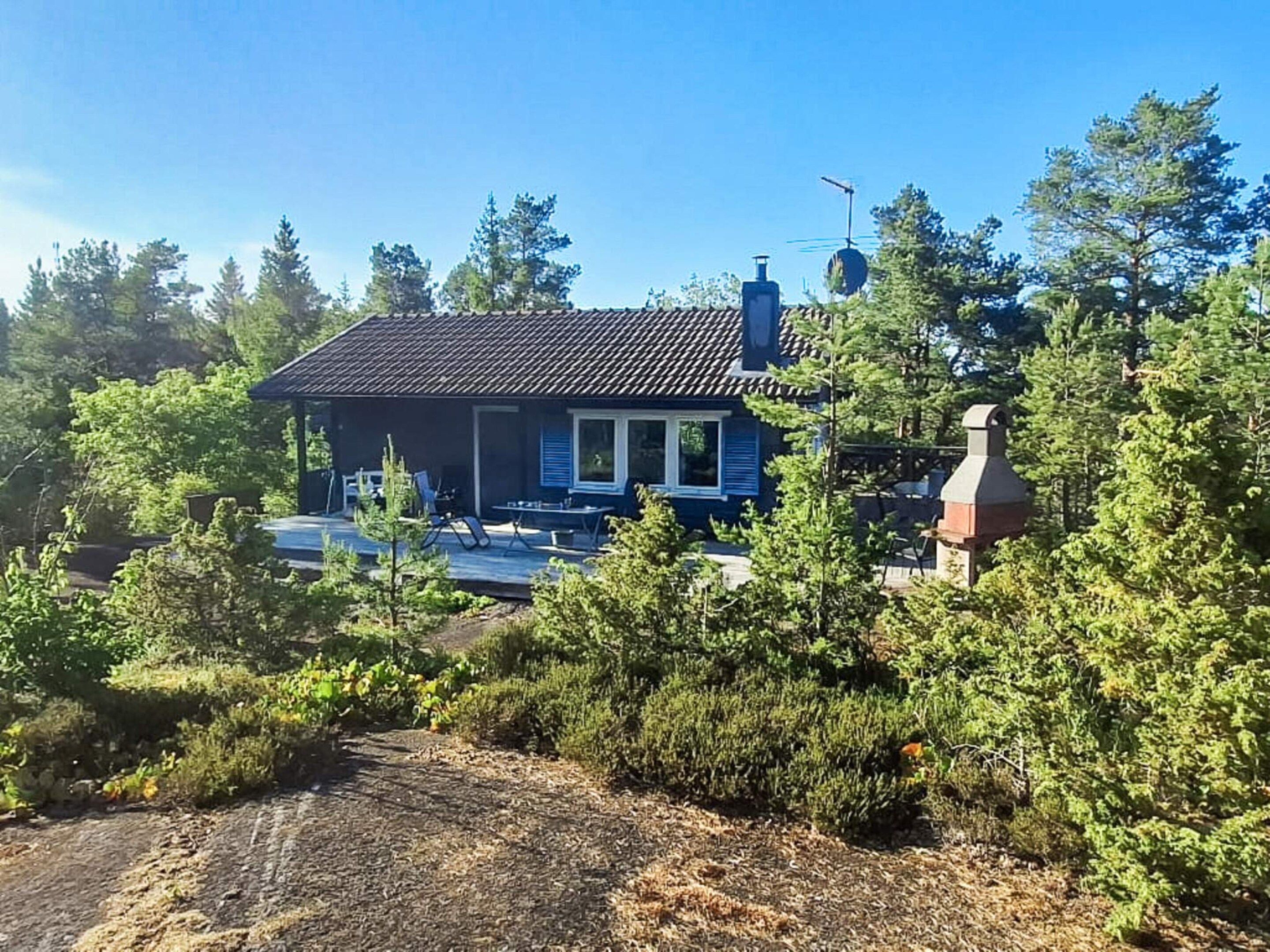 Uma casa com telhado inclinado, chaminé e varanda com móveis de exterior.