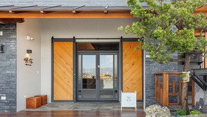 A hotel entrance with a sliding glass door, a stone wall, and a wooden deck. - Between River and Sea (Wujie)