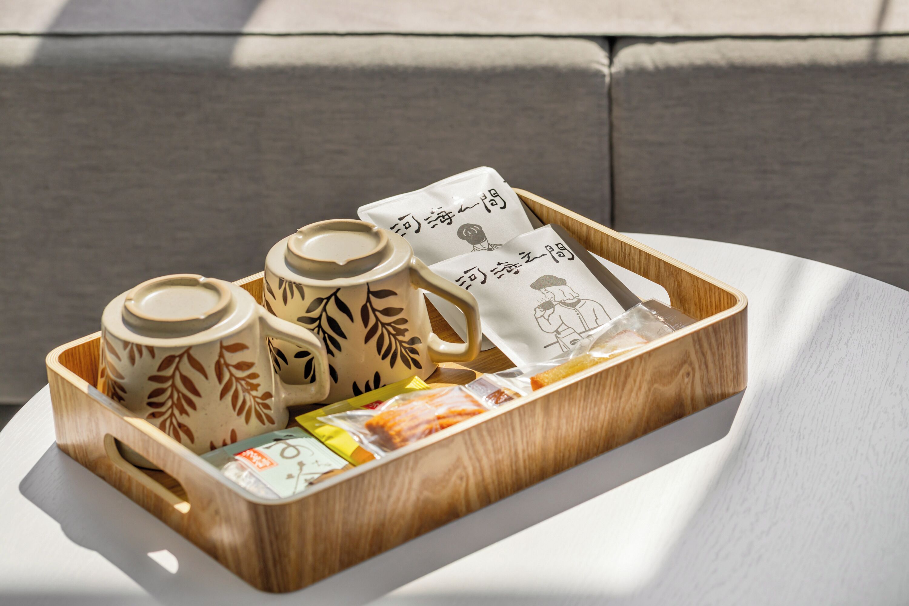 A wooden tray with ceramic cups and tea bags on a table.