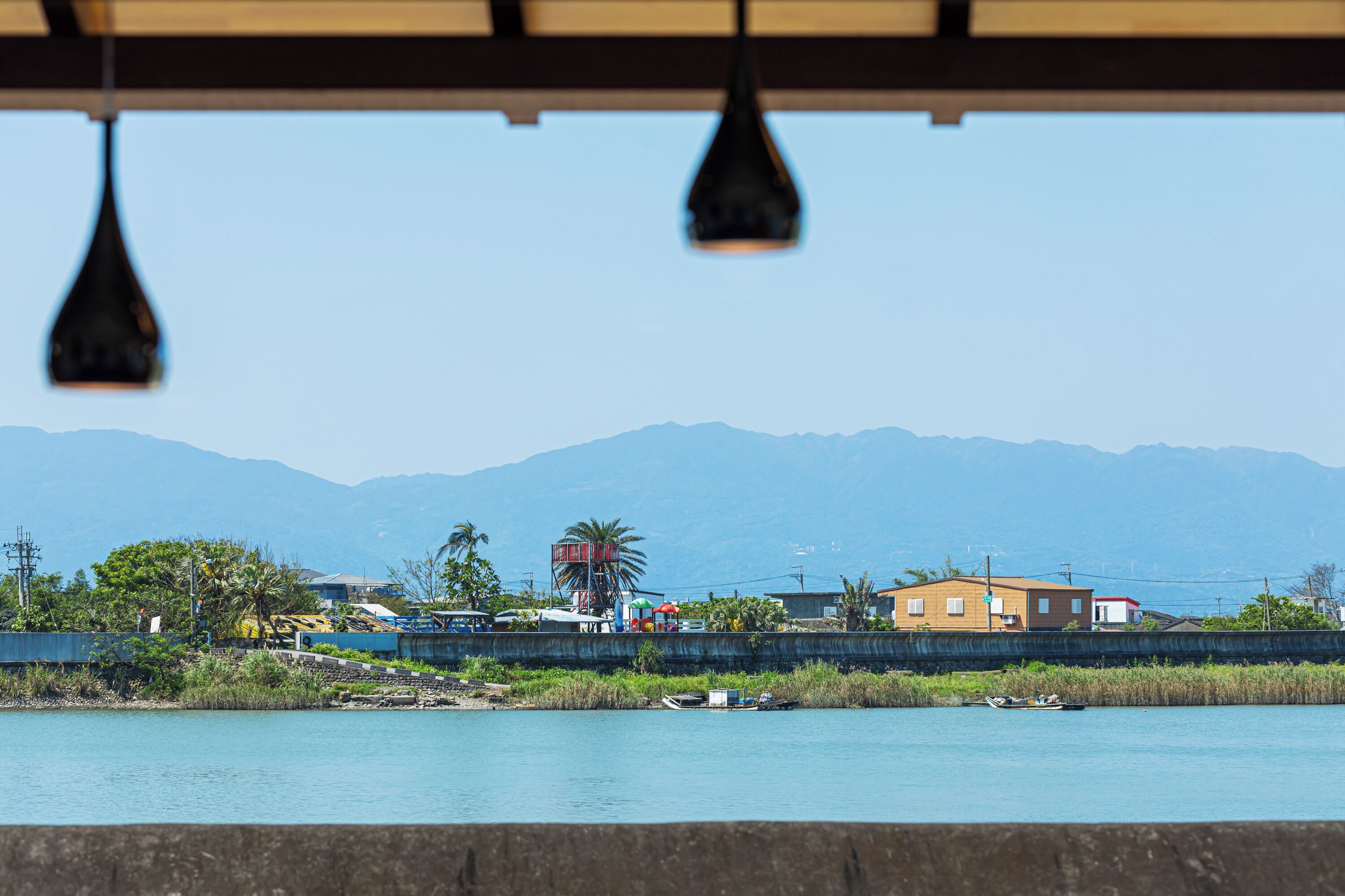 Une vue sur la côte, avec un ciel dégagé, des montagnes en arrière-plan et un bâtiment à toit rouge situé près de l’eau.