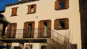 A multi-story building with wooden shutters on windows, a balcony with a metal railing, and a chimney. - Cosy mountain home ideal for families and friends. (Angoustrine-Villeneuve-des-Escaldes)