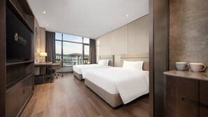 Une chambre d’hôtel avec deux lits, un bureau, une télévision et une grande fenêtre donnant sur la ville.