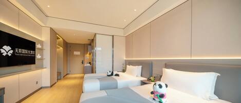 A hotel room with two beds, a television, and a panda plush toy.