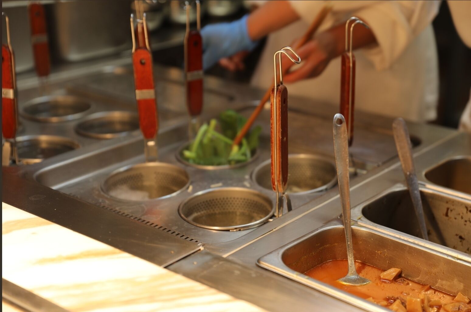 Una cocina con lavamanos de acero inoxidable y utensilios.