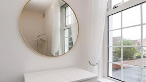 A bathroom with a white vanity, a round mirror, and a window with a view of buildings outside. - Kitty Cottage - 3 Bedroom - Warm and Welcoming - Sleeps 5 - Blackpool (Blackpool)