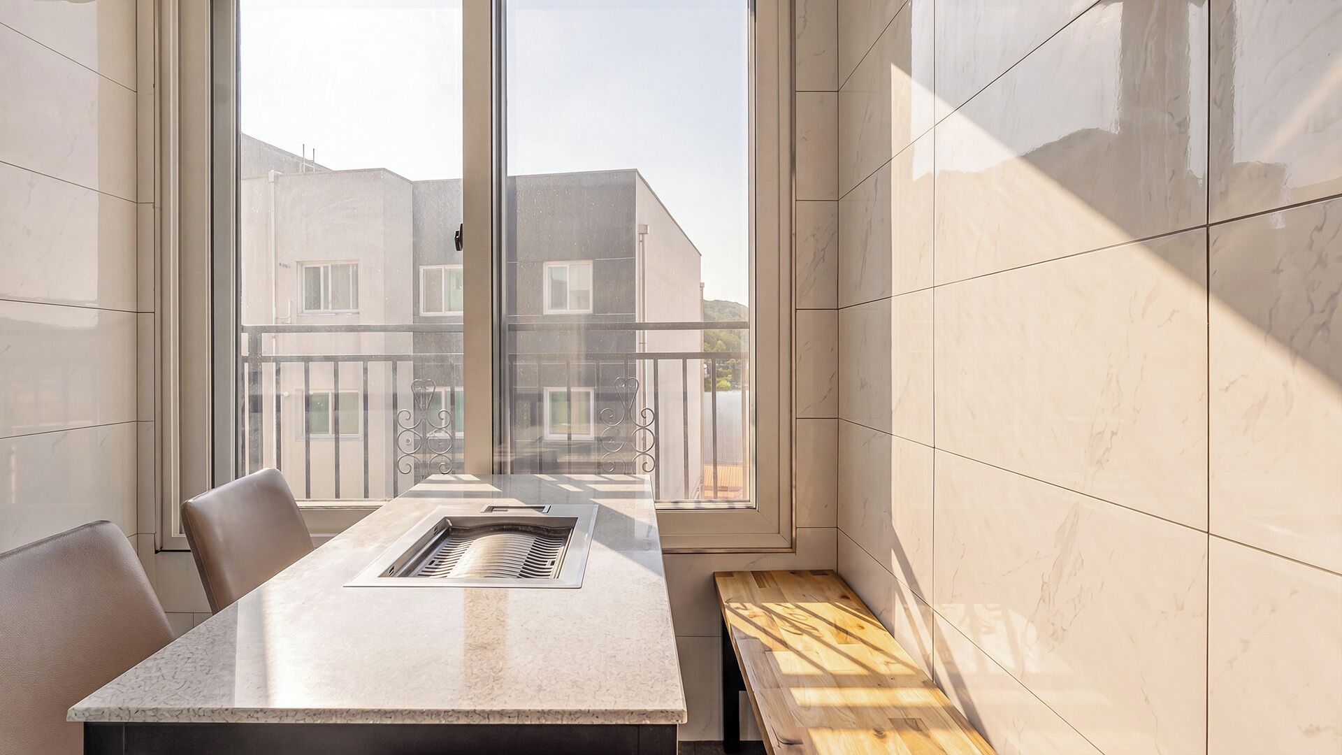 Un intérieur moderne avec un comptoir en marbre, un banc et une vue sur les bâtiments à travers de grandes fenêtres.