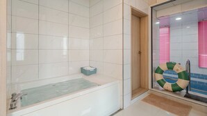 A bathroom with a bathtub, a shower area, and a glass door leading to a pool area. - Gapyeong Binchelo Pool Villa Spa Pension (Gapyeong)