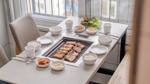 A dining table with a grill, bowls of rice, kimchi, and other side dishes. - Gapyeong Binchelo Pool Villa Spa Pension (Gapyeong)
