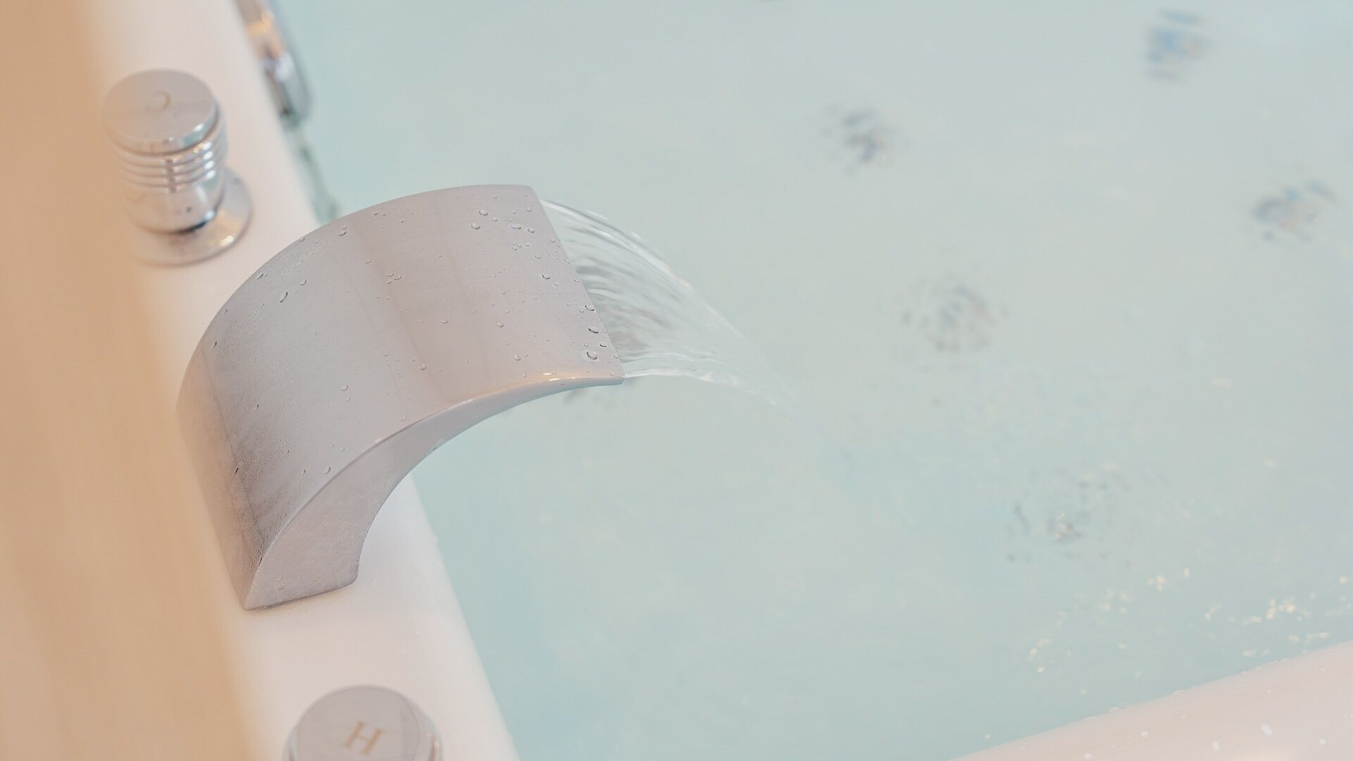 A bathtub with a curved faucet and water flowing into it.