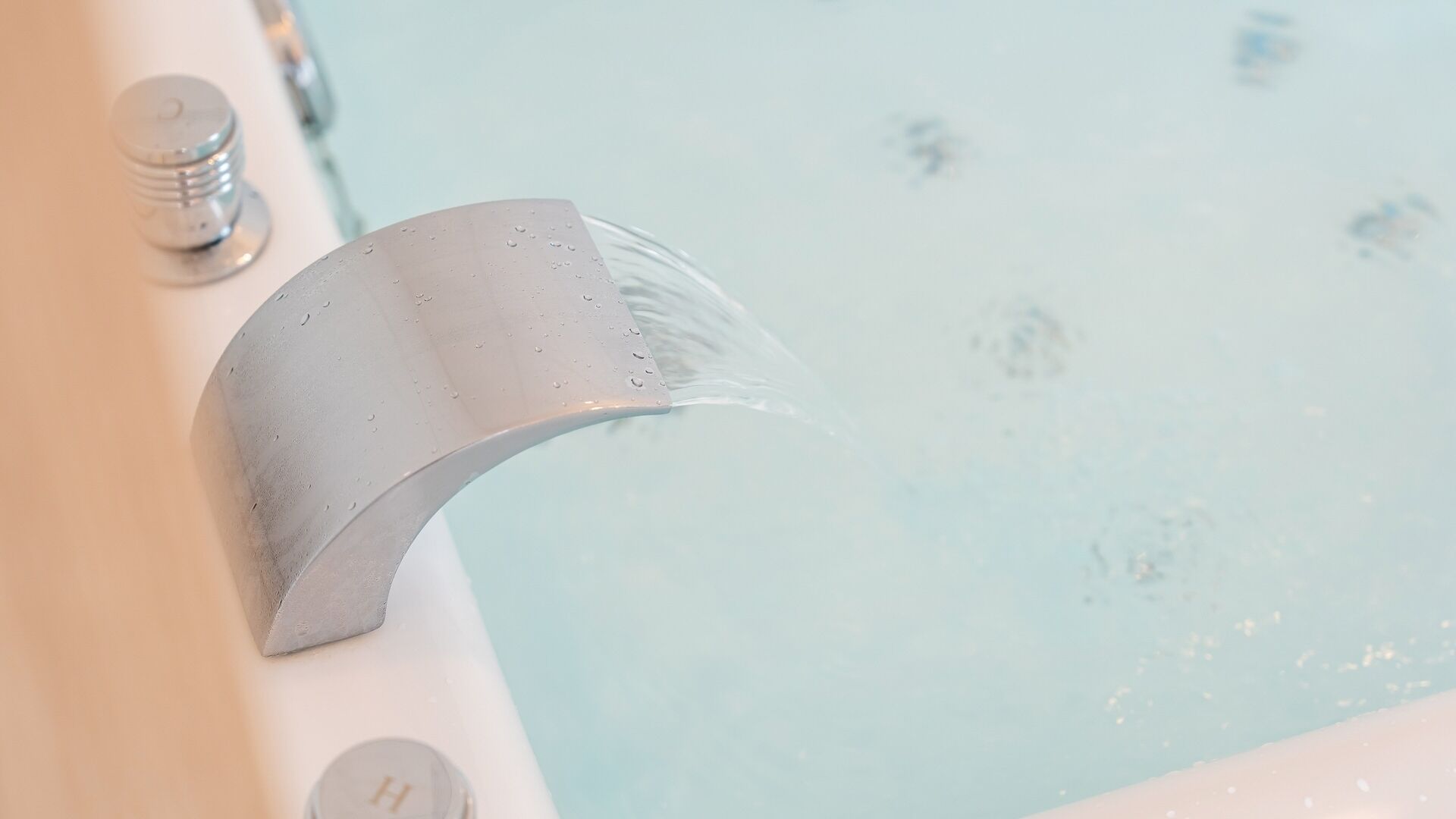 A bathtub with water flowing from a curved spout.