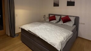 Une chambre à coucher avec un lit, un luminaire suspendu et deux tableaux accrochés au mur.