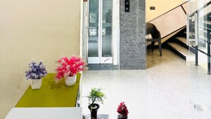 Un hall d’entrée avec une horloge, un comptoir d’accueil, un escalier et une porte dotée d’un panneau en verre.