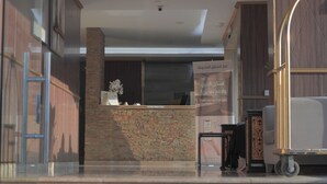 A reception area with a stone pillar, a reception desk, and a signboard. - Lamar Taiba Serviced Apartment (Madinah)