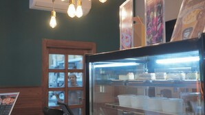 A bakery display case with desserts and a menu board. - Lamar Taiba Serviced Apartment (Madinah)