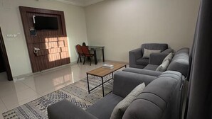 A modern living room with a grey sofa set, a wooden coffee table, and a patterned rug. - Lamar Taiba Serviced Apartment (Madinah)