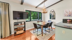 A modern kitchen with a dining area, large windows, and a chandelier.