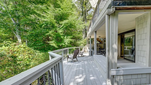 A wooden deck with chairs, surrounded by trees.
