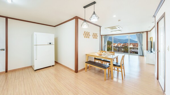 Una cocina moderna con un refrigerador blanco, una mesa de comedor de madera y sillas, y lámparas colgantes.