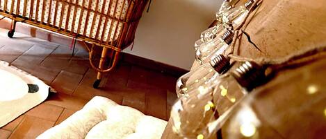 Una habitación con una cuna de madera, un sofá estampado y una botella de vidrio con corcho.