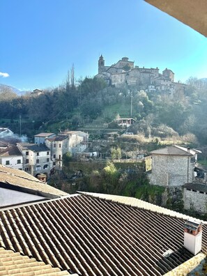 A historic town with stone buildings and a prominent castle on a hill. - Il suono del fiume (Bagnone)