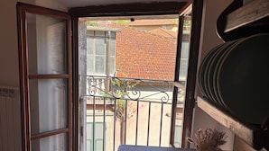 A corner room with a wooden table, a potted plant, and a view of a tiled roof and greenery outside. - Il suono del fiume (Bagnone)