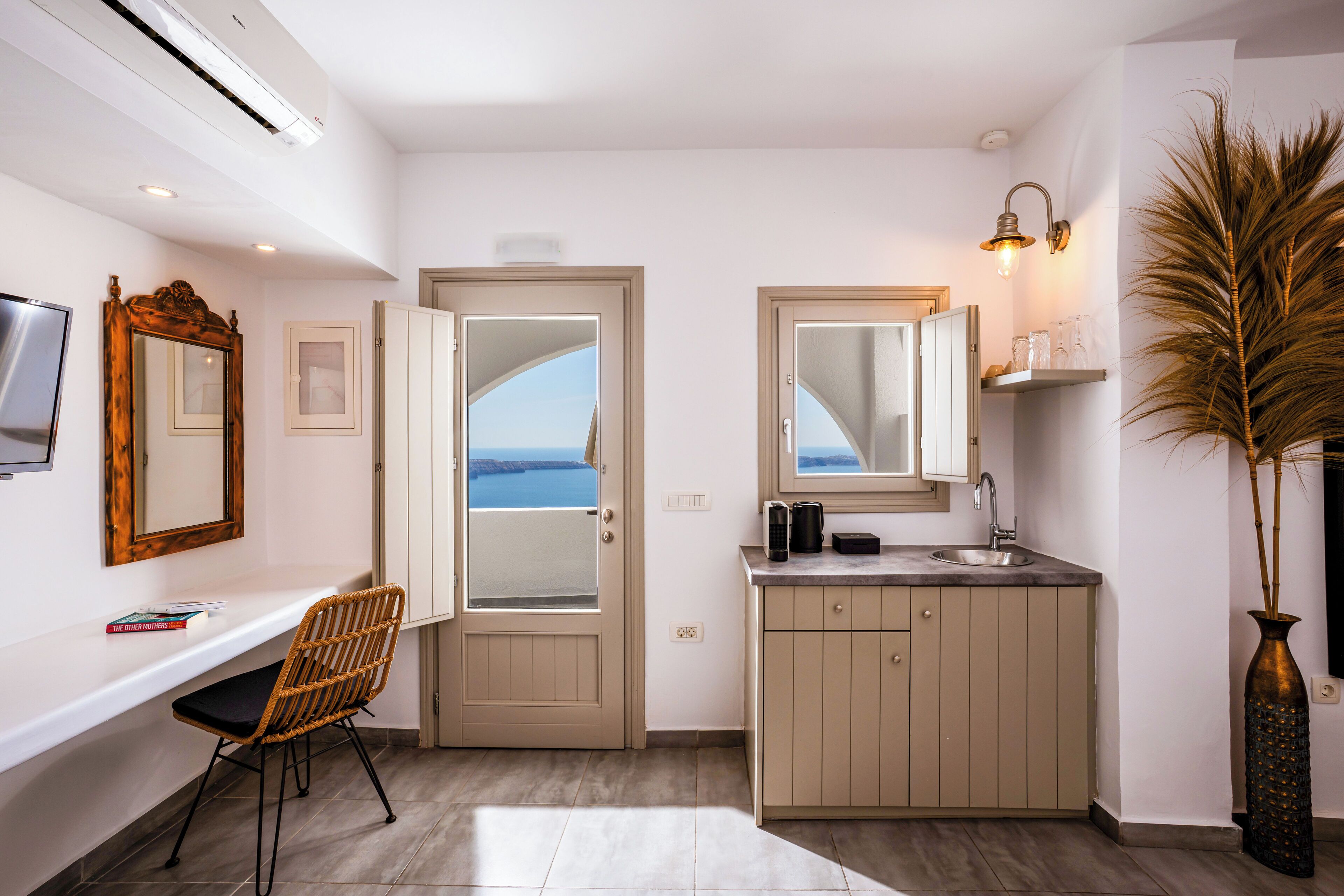 A modern kitchen with a view of the sea, a dining area with a chair, and a large mirror.