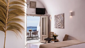 Une chambre avec un lit, un coin repas avec des chaises et une table, et une vue sur la mer.