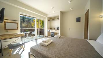 Une chambre moderne avec un grand lit, un bureau et une vue sur un balcon.