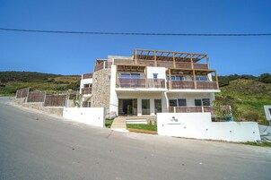 Una casa moderna de dos pisos con balcón, fachada de piedra y vistas despejadas del paisaje circundante.