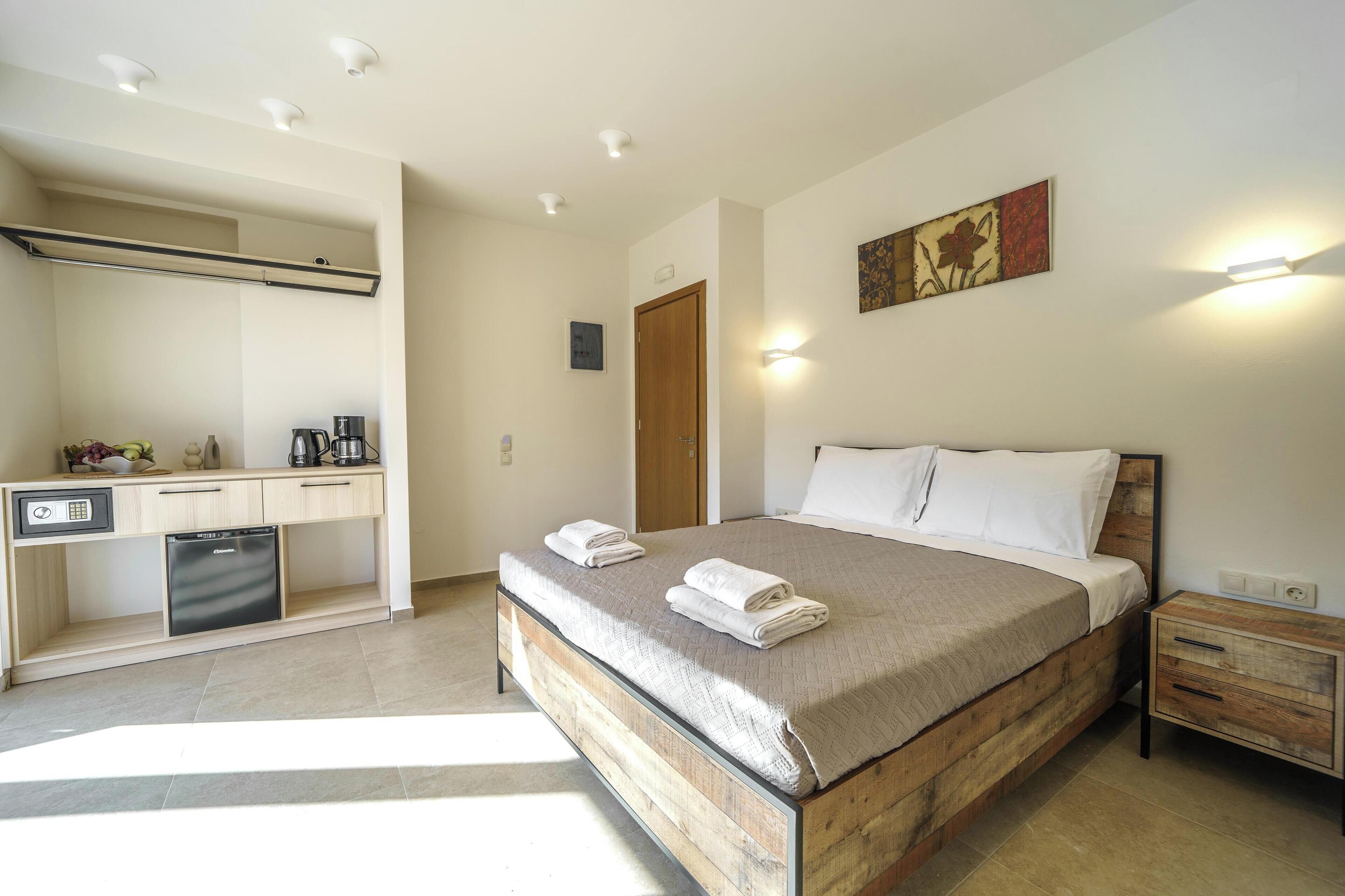 A bedroom with a wooden bed, bedside tables, a desk with a coffee machine, and a built-in dishwasher.
