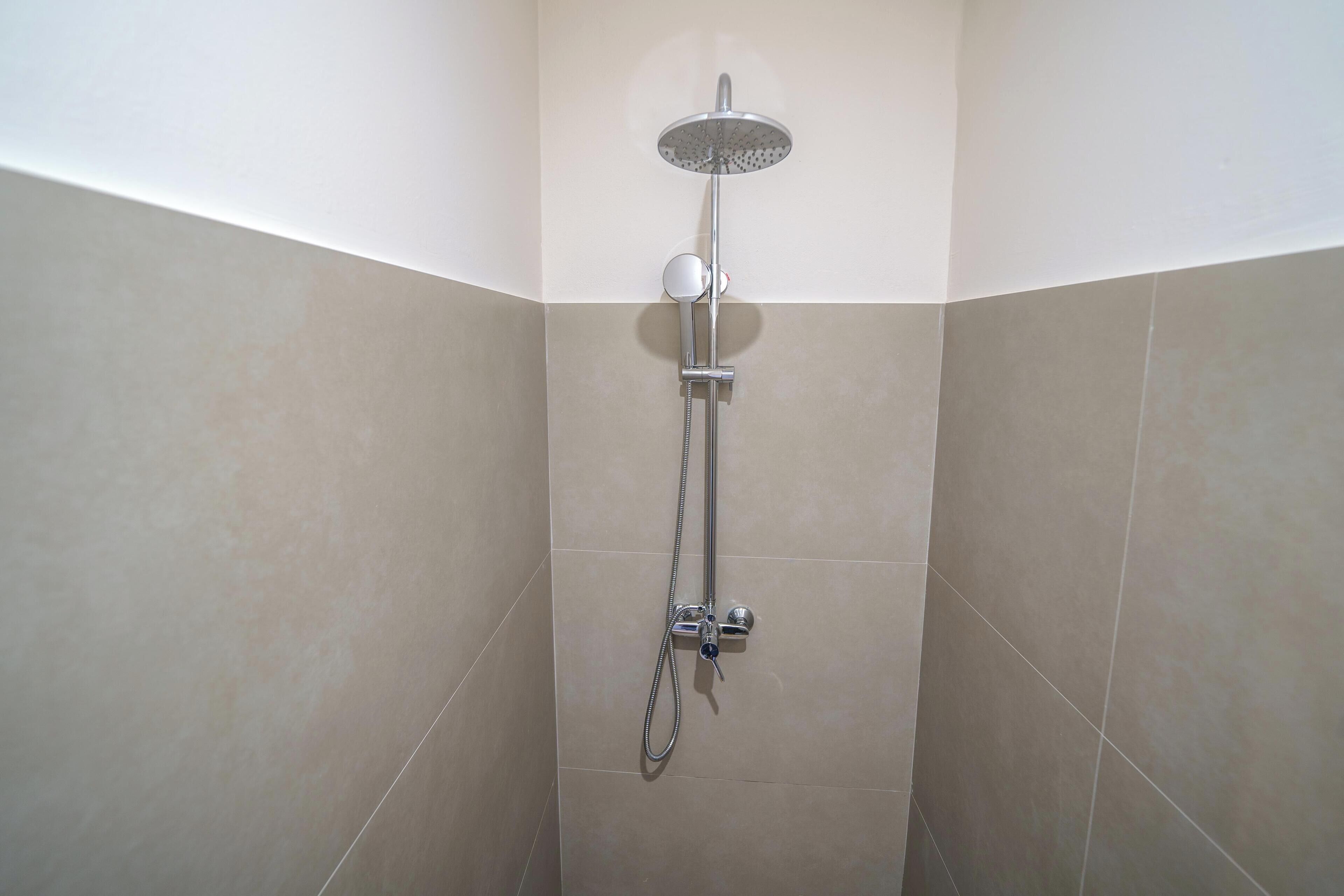 A shower with a handheld showerhead and a wall-mounted faucet.