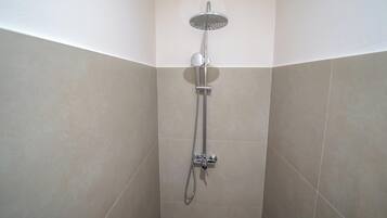 A shower with a handheld showerhead and a wall-mounted faucet.