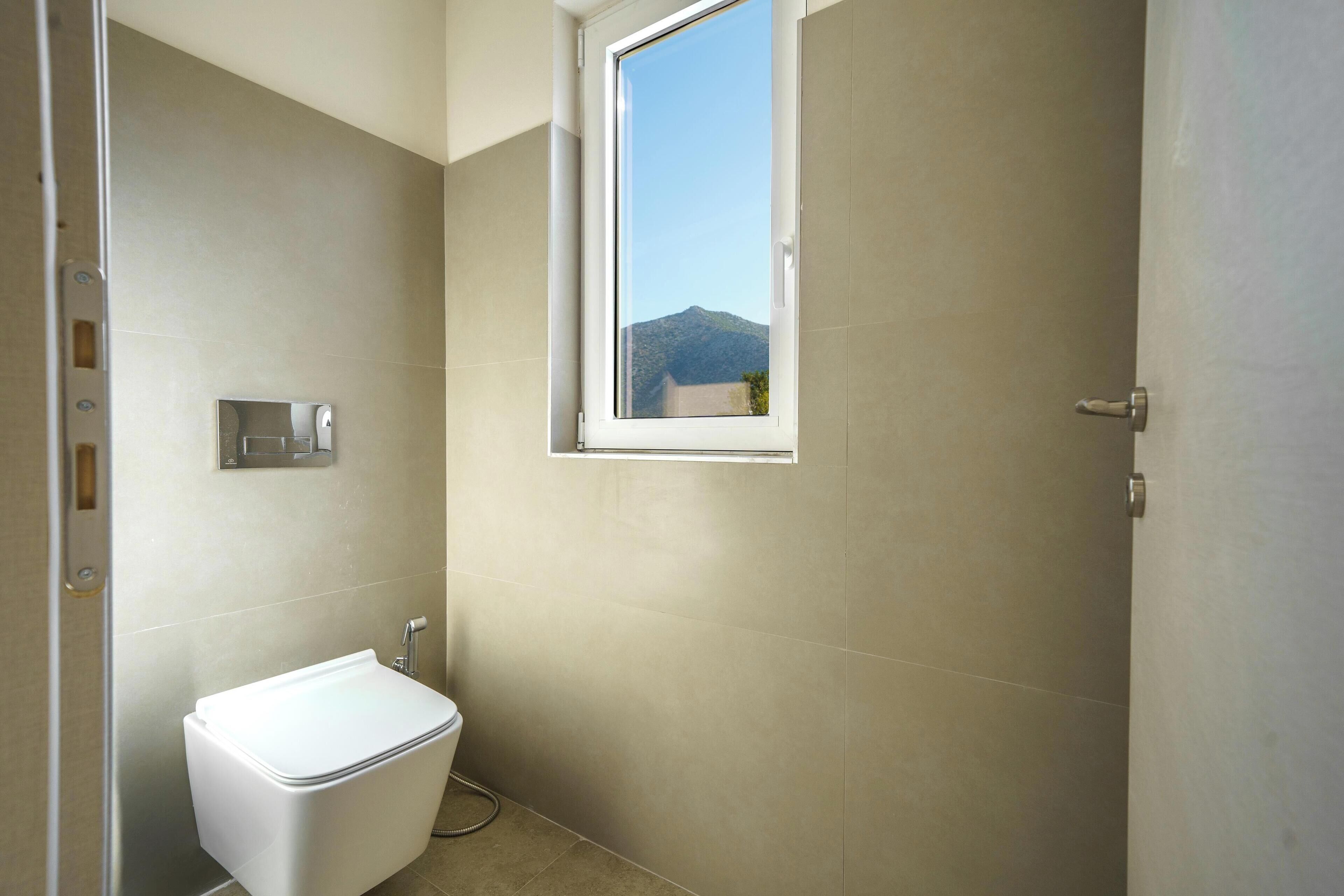 Ein kleines Badezimmer mit Toilette, Fenster und Dusche.